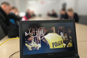 Na zdjęciu widoczny ekran laptopa z wyświetlonym kadrem, na którym znajdują się umundurowani policjanci.