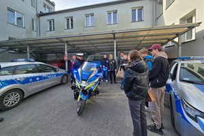 Na zdjęciu widoczny przy motocyklu policjant z drogówki. Wokół zgromadzeni uczestnicy spotkania.