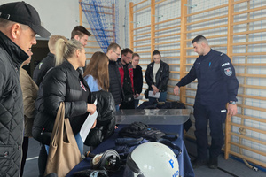 Na zdjęciu widoczny policjant, który prezentuje policyjny sprzęt uczestnikom spotkania.