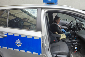 Na zdjęciu widoczna kobieta, która siedzi za kierownicą radiowozu.