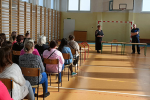 Na zdjęciu widoczny policjant oraz biorący udział w spotkaniu opiekunowie.