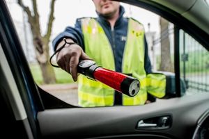 Na zdjęciu widoczny policjant, który kieruje alcosensor do środka pojazdu.