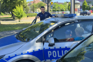 Na zdjęciu widoczny policjant oraz dzieci wsiadające do radiowozu.