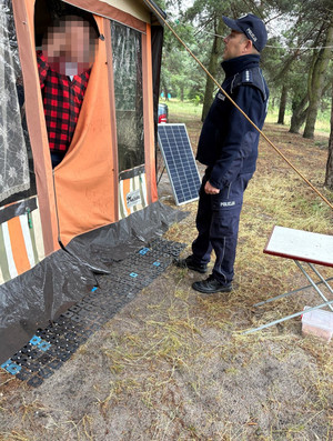 Na zdjęciu widoczny policjant, podczas kontroli wypoczywających na terenach zalesionych osób.