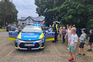 Na zdjęciu widoczny radiowóz, policjant oraz uczestnicy półkolonii.