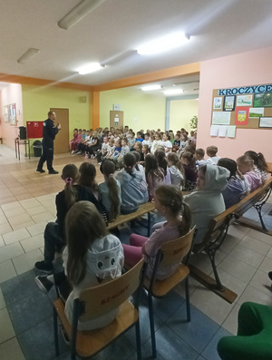 Na zdjęciu widoczny aspirant Dariusz Grajkowski z dziećmi i młodzieżą, podczas spotkania profilaktycznego.