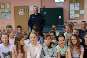 Na zdjęciu widoczny aspirant Dariusz Grajkowski z dziećmi i młodzieżą, podczas spotkania profilaktycznego.