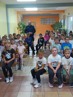 Na zdjęciu widoczny aspirant Dariusz Grajkowski z dziećmi i młodzieżą, podczas spotkania profilaktycznego.