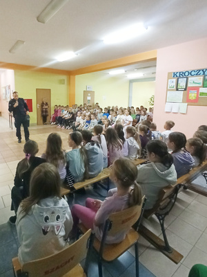 Na zdjęciu widoczny aspirant Dariusz Grajkowski z dziećmi i młodzieżą, podczas spotkania profilaktycznego.