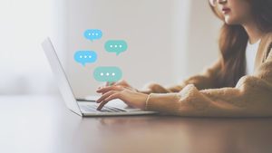 Na zdjęciu widoczna częściowo dziewczyna, która pisze na laptopie.