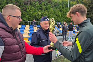 Na zdjęciu widoczny Pierwszy Zastępca Komendanta Powiatowego Policji w Zawierciu podinspektor Paweł Sobota oraz przedstawiciel zawierciańskiego Zarządu Terenowego NSZZ Policjantów aspirant sztabowy Dawid Cacoń, który wręcza puchar zawodnikowi.