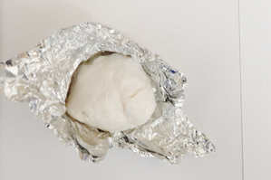 Na zdjęciu widoczna biała, zbrylona substancja w folii aluminiowej.