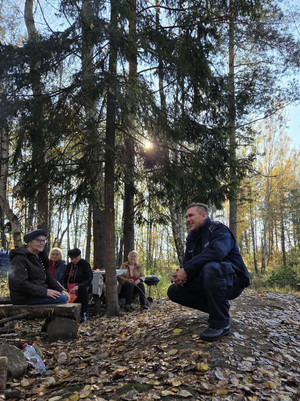 Na zdjęciu widoczny policjant na spotkaniu z seniorkami w lesie.