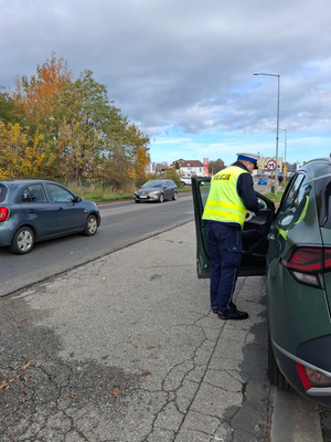 Na zdjęciu widoczny policjant w trakcie kontroli drogowej pojazdu.