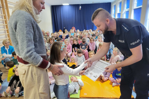 Na zdjęciu widoczny policjant, któremu dziewczynka wręcza dyplom. Policjant dziękuję dziewczynce uściskiem dłoni.