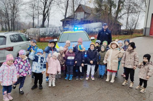 Zdjęcie grupowe. Policjant oraz dzieci stoją przed radiowozem.