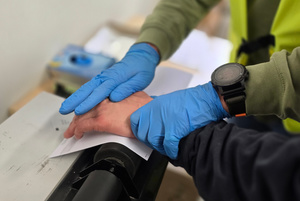 Na zdjęciu widoczne pobieranie odbitek linii papilarnych od zatrzymanego.