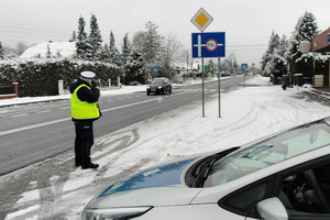 Na zdjęciu widoczny policjant, który mierzy prędkość jazdy samochodu.