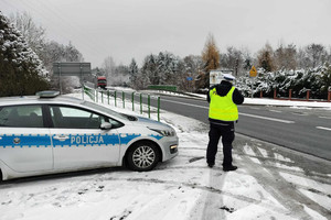 Na zdjęciu widoczny policjant, który mierzy prędkość jazdy samochodu.