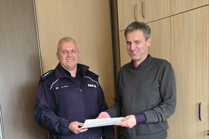 Na zdjęciu widoczny aspirant Damian Opydo, który przekazuje plakaty Olafowi Błasikowi - pełnomocnikowi zarządu spółdzielni.