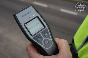 Na zdjęciu widoczne urządzenie do badania stanu trzeźwości trzymane w ręku przez policjanta.