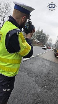 Na zdjęciu widoczny policjant, który mierzy prędkość pojazdu.