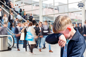 Na zdjęciu widoczny chłopiec, który zasłania ręką twarz. Dziecko znajduje się w zatłoczonej galerii handlowej.