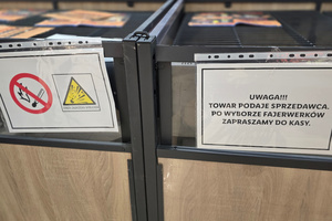 Na zdjęciu widoczne tabliczki ostrzegawcze przy stoisku z fajerwerkami.