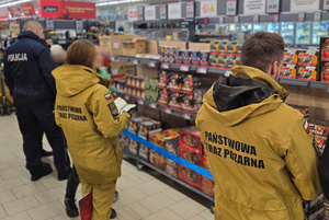 Na zdjęciu widoczny policjant i strażacy podczas kontroli punktu sprzedaży fajerwerków.