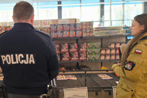 Na zdjęciu widoczni policjant i przedstawicielka straży pożarnej podczas kontroli punktu sprzedaży fajerwerków.