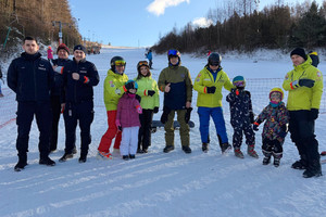 Zdjęcie grupowe policjantów i narciarzy na stoku.