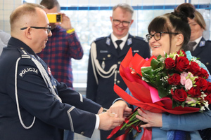 Na zdjęciu widoczny inspektor Artur Klimek, który wręcza bukiet kwiatów swojej małżonce.