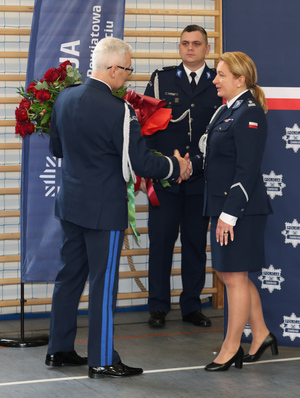 Na zdjęciu widoczny Komendant Wojewódzki Policji w Katowicach nadinspektor Mariusz Krzystyniak, który wręcza bukiet kwiatów młodszemu inspektorowi Renacie Hałabudzie.