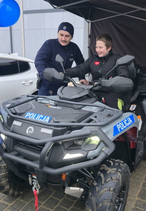 Na zdjęciu widoczny policjant przy quadzie, na którym siedzi chłopiec.