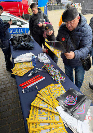 Na zdjęciu widoczny umundurowany policjant oraz osoby przy stoisku profilaktycznym.