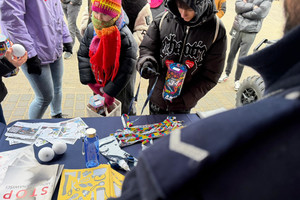 Na zdjęciu widoczny częściowo policjant oraz osoby przy stoisku profilaktycznym.