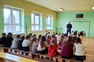 Na zdjęciu widoczny policjant, który prowadzi spotkanie z uczniami.