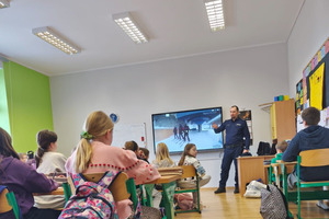 Na zdjęciu widoczny policjant i uczniowie podczas spotkania profilaktycznego.