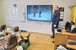 Na zdjęciu widoczny policjant i uczniowie podczas spotkania profilaktycznego.