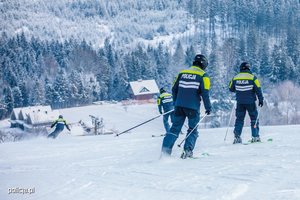 Na zdjęciu widoczni policjanci patrolujący stok na nartach.