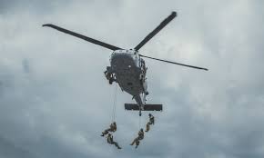 Na zdjęciu widoczny helikopter i zjeżdżające z niego po linach osoby.