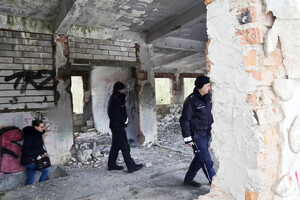 Na zdjęciu widoczni policjanci oraz kobieta, kontrolujący pustostan.