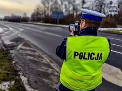 Na zdjęciu widoczny policjant mierzący prędkość pojazdów.