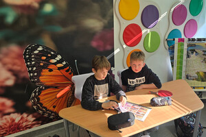 Na zdjęciu widoczni dwaj uczniowie, którzy przeglądają broszurę ze zdjęciami.