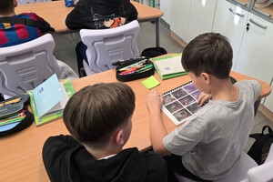 Na zdjęciu widoczni dwaj uczniowie, którzy przeglądają broszurę ze zdjęciami.