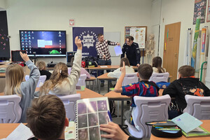 Na zdjęciu widoczny umundurowany i nieumundurowany policjant na spotkaniu z uczniami.