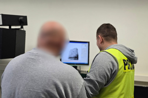 Na zdjęciu widoczny mężczyzna podczas skanowania zdjęć linii papilarnych przez technika kryminalistyki.
