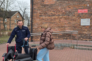 Na zdjęciu widoczny dzielnicowy oraz przedstawicielka Miejskiego Ośrodka Kultury w Zawierciu, której policjant przekazuje dwa wózki inwalidzkie oraz komplet kuli ortopedycznych.