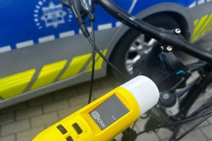 Na zdjęciu widoczny częściowo radiowóz, rower oraz urządzenie do badania stanu trzeźwości.