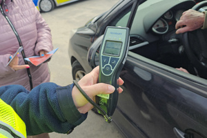 Urządzenie do badania stanu trzeźwości trzymane przez policjantkę w ręku. Na urządzeniu widoczny wyświetlony napis: Brak alkoholu.